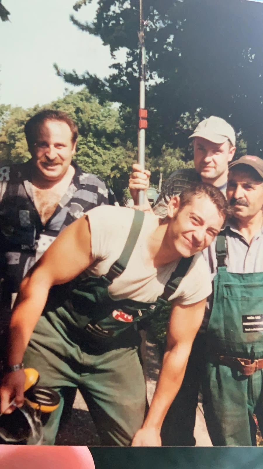 Historisches Teamfoto: vier Personen in grüner Arbeitskleidung mit Freischneider und Teleskop-Heckenschere
