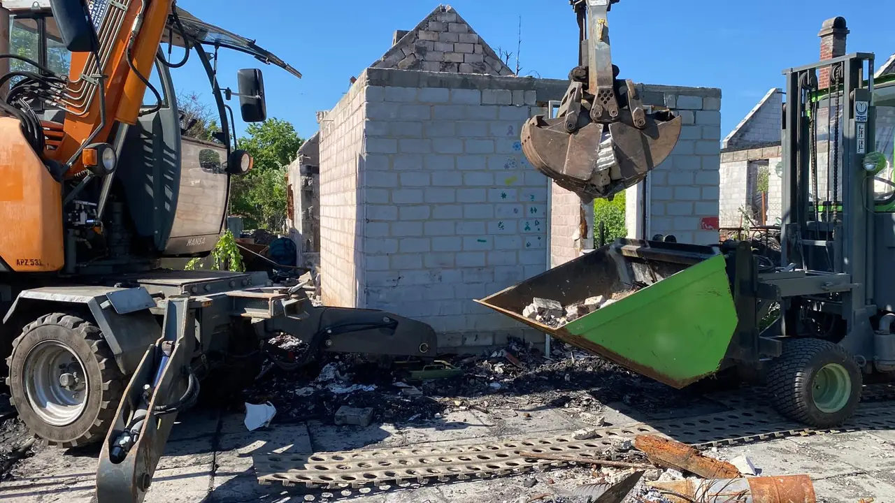 Bagger mit Greifer räumt Brandschutt — Abrissarbeiten FÖH Baumgala